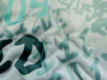 Nahaufnahme von einem kuschligen Fleece in grau mit Schriftzügen 
